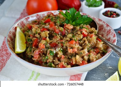 Snack salad of roasted eggplant with garlic and tomato on a concrete background