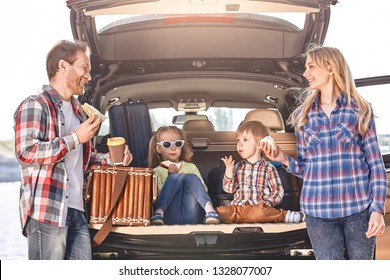 Snack Time. Family Stands Near The Car, Having A Lunch. Family Road Trip