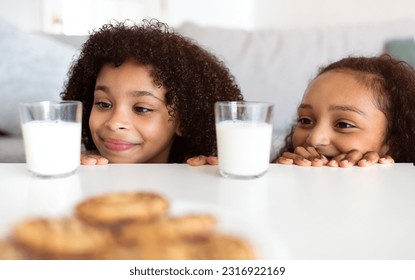 Snack Time. Happy African American Siblings Girls Having Lunch Together, Looking At Tasty Cookies And Milk In Glasses On Table At Home. Preteen Kids Enjoying Healthy Snacks. Nutrition Concept - Powered by Shutterstock