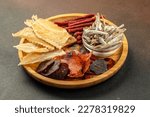 snacks for beer, Dried fish mix on wood plate. dried fish chorizo sausage meat carpaccio on a dark background. place for text, top view.