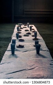 Snacks for drinking beer. Long table served with plastic cups and plates of crumbs or dentels in dark place.