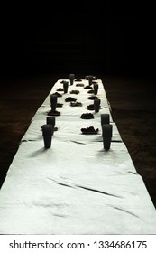 Snacks for drinking beer. Long table served with plastic cups and plates of crumbs or dentels in dark place.