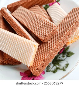 Snacks made of crunchy and sweet sugar powder called wafer. Wafer on a small white plate with floral motif.  - Powered by Shutterstock