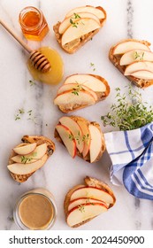 Snacks made of toast with nut butter, apple and honey on a marble background with thyme sprigs