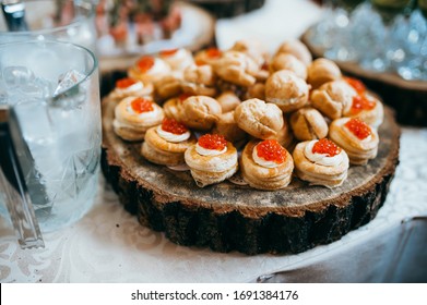 Snacks On The Wedding Table. Different Canapes On A Wooden Plate