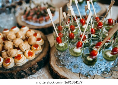 Snacks On The Wedding Table. Different Canapes On A Wooden Plate