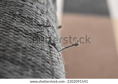 Snagged thread from cat scratches on a cushion cover.  Selective focus.   Copy space is on the right. 