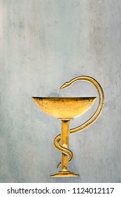 Snake with cup, symbol of medicine on stone background. Medical sign bowl of Hygieia. Snake on bowl of Hygeia - antique sign of Pharmacy. design for medical theme. Copy space
