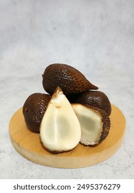 Snakefruit or salak. Salak pondoh or Salacca Zalacca grows in the West and South of Java and South Sumatra. Peeled salak fruit isolated on white background. Bunch of salak on wooden plate.
