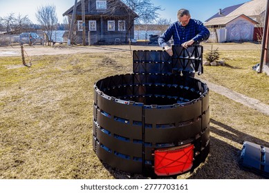 Snap together assembly modular compost bin, farmer installing mass produced composter near farmhouse.