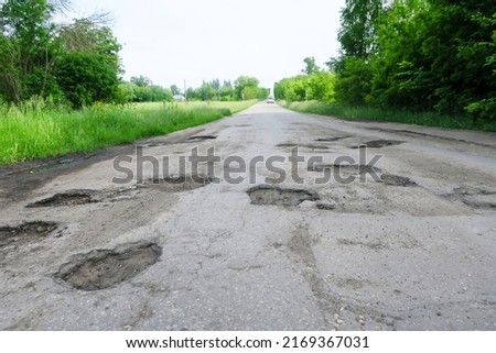 A snapshot of old cracked asphalt in need of repair. The road is full of holes and potholes.                      