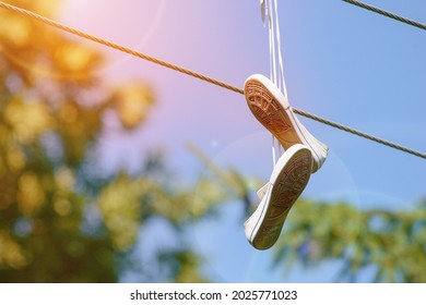 Sneakers hanging on the power lines. Shoe tossing. Fun or marking territory.