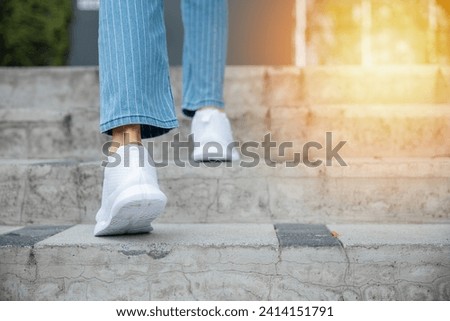 With sneakers on, a woman takes on the city stairway, showcasing her determination and progress. Each step is a reflection of her unwavering journey towards success and personal growth. step up