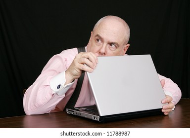 Sneaky Businessman Peeking Over A Laptop Computer Good For Corporate Theft Or Protection Concepts