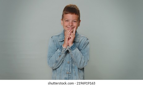 Sneaky Cunning Boy With Tricky Face Gesticulating And Scheming Evil Plan, Thinking Over Devious Villain Idea, Cunning Cheats, Jokes And Pranks. Toddler Teenager Child On Gray Studio Background Alone