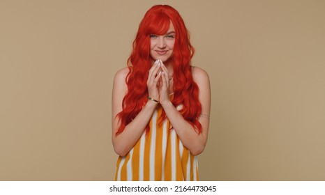 Sneaky cunning woman with tricky face gesticulating and scheming evil plan, thinking over devious villain idea, cunning cheats, jokes and pranks. Redhead girl on beige studio background alone indoors
