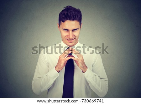 Sneaky scheming man trying to plot something isolated on gray background. Negative human emotion facial expression feeling