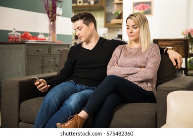 Sneaky Young Man Texting His Lover While Sitting Next To His Girlfriend At Home