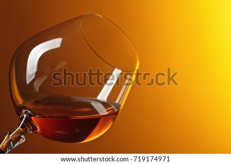 Snifter of brandy with copy space for text on a yellow background.
