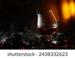 Snifter of brandy on a burning charcoal. Concept of hard alcoholic drinks. Copy space.