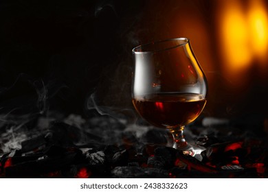 Snifter of brandy on a burning charcoal. Concept of hard alcoholic drinks. Copy space.