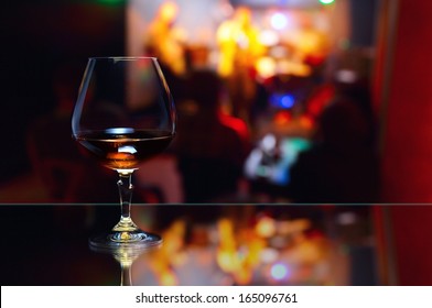 Snifter With Brandy On Glass Table In Nightclub