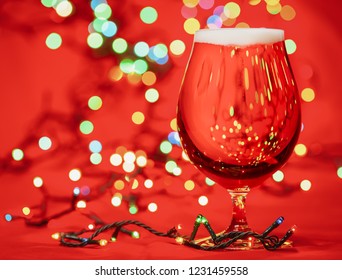 Snifter Glass Of Pale Lager Beer Or Ale With  Christmas Lights On Red Background