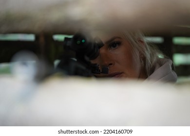 A Sniper Girl Aims From A Rifle From Behind A Shelter In The Forest.