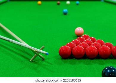 The Snooker Balls On The Table Consisted Of Red, Black, Pink, Blue, Green, White, Brown, And Yellow, With A Cue Placed On Wood On The Side.