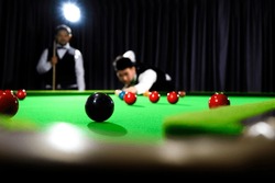 Snooker Schwarz Ein Ball Und Snooker-Spieler Mit Unscharfem Konkurrenten, Während Sie Schwarzen Ball Auf Snooker-Tisch Im Hintergrund.