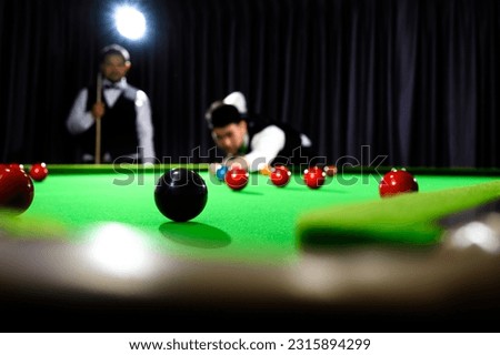 Snooker black one ball and snooker player with competitor blur while aiming black ball on snooker table in background.