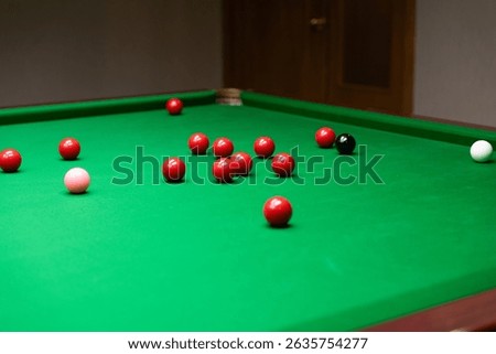 A snooker table with red, black, pink, and white balls scattered