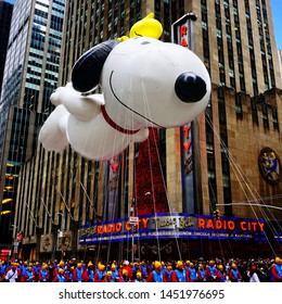 Snoopy balloon floats in the air during the annual Macy's Thanksgiving Day parade along Avenue of Americas with the Radio Music Hall in the background. Manhattan, New York, USA - November 27, 2014.