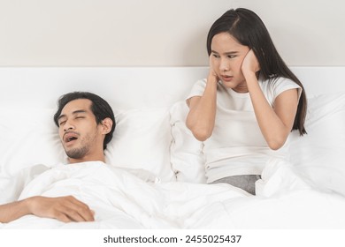 Snoring couple health asian man snore and sleeping at home while woman insomnia annoyed, bad noise cover ears with hand sleep problem apnea and relationship, wife looking at husband snoring in bed. - Powered by Shutterstock