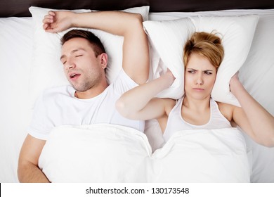 Snoring Man And Young Woman. Couple Sleeping In Bed.