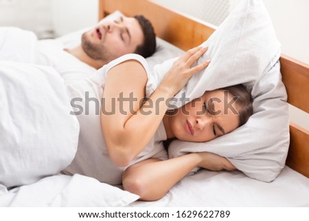 Snoring. Unhappy Girlfriend Trying To Sleep Near Snorting Boyfriend In Bed Indoor. Selective Focus