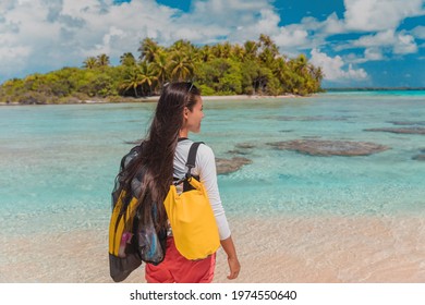 Snorkel water sport activity. Young Asian woman on snorkeling adventure travel vacation walking with mask and fins. French Polynesia Tahiti island coral reef lagoon in Pacific Ocean. Rangiroa atoll.