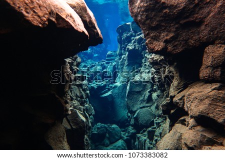 Snorkeling and scuba diving in popular touristic Icelandic fissure Silfra, blue underwater lava rocks