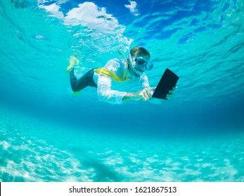 Snorkelling businessman in shirt and tie and matching fins using a tablet computer while swimming under water in tropical turquoise sea - Powered by Shutterstock