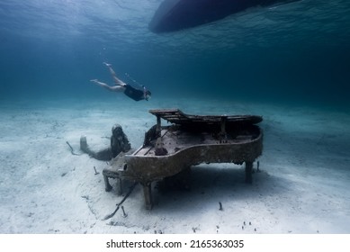 A snorkler swims by an underwater statue of a Mermaid next to a Piano, located in the Bahamas in the Caribbean  - Shutterstock ID 2165363035
