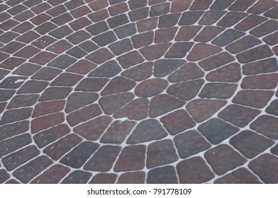 Snow Adds To Circular Design Pattern Of Sidewalk Made Of Gray And Maroon Concrete Brick Pavers