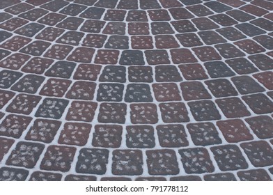 Snow Adds To Circular Design Pattern Of Sidewalk Made Of Gray And Maroon Concrete Brick Pavers