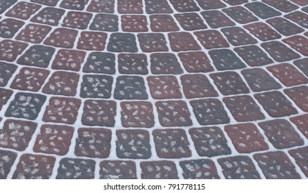 Snow Adds To Circular Design Pattern Of Sidewalk Made Of Gray And Maroon Concrete Brick Pavers