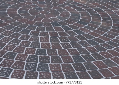 Snow Adds To Circular Design Pattern Of Sidewalk Made Of Gray And Maroon Concrete Brick Pavers