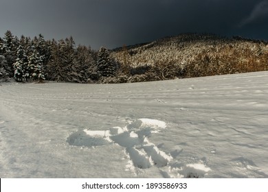 Snow Angel In The Fresh Snow. Trace From The Human Adult Body In Winter Landscape.Print Of Body Copy Space.Crime Scene In Nature, Shape Of Body Snow Texture.Fun Joy On Winter Holidays Stormy Clouds