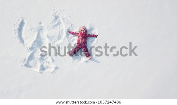 Snow angel made by a kid in the snow. Overhead point\
of view