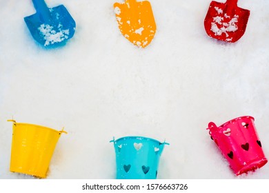 Snow Background For Christmas Scenes Or New Year Cleaner Concept With Colorful Funny Toy Snow Shovel And Bucket Red Yellow Blue Above White Snowflake Top View With Copy Space For Winter Happy Holiday