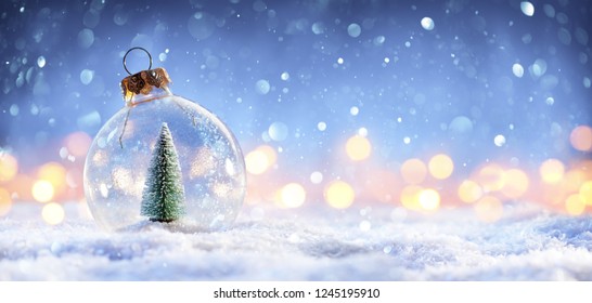 Snow Ball With Christmas Tree In It And Lights On Winter Background
					