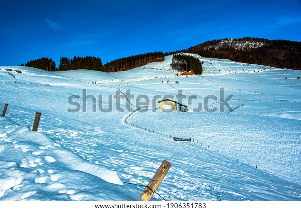 snow between mountains and\
valleys with beaten path divided by barbed wire in Asiago, Vicenza,\
Italy