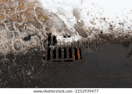 Snow blocking storm drain gutter ice footprints water cold ice